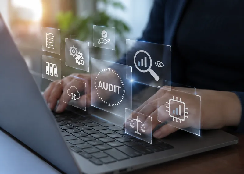 Hands on a laptop with floating audit and finance icons