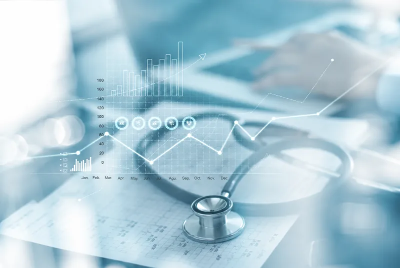 Stethoscope on a desk beside digital health charts
