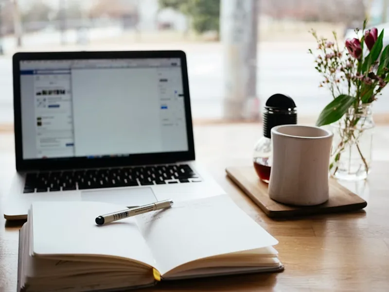Laptop, open notebook and coffee mug on a study desk
