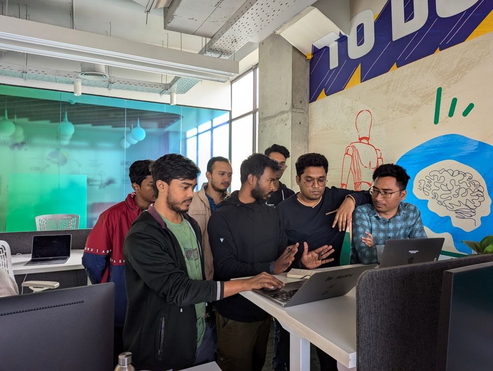 A team of young engineers gathered around a laptop in a bright office