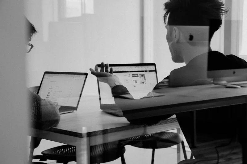 Black-and-white photo of a person working at a laptop at a desk