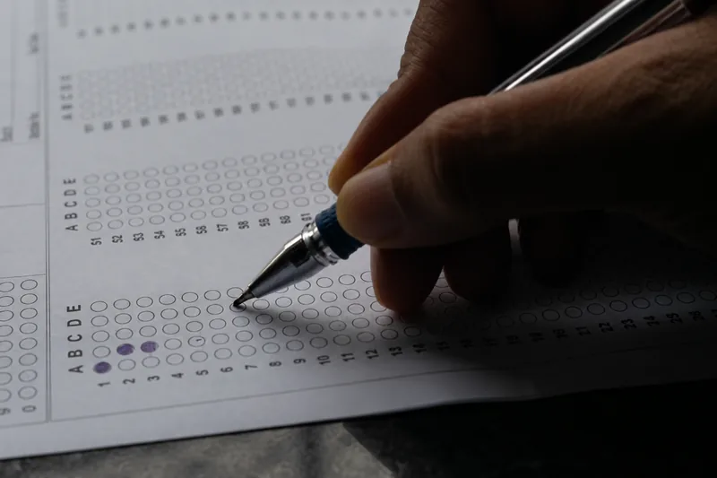 Hand filling in an OMR answer sheet with a pen