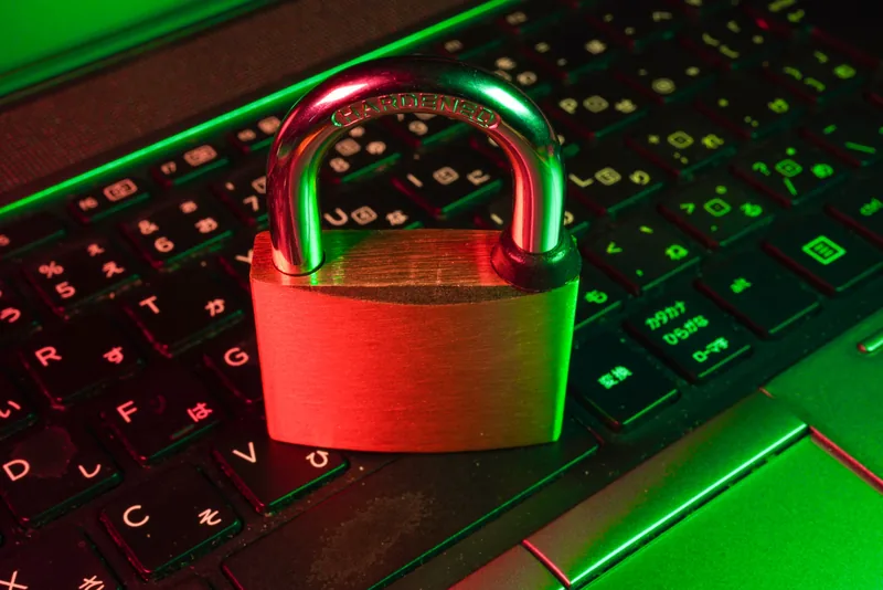 Red padlock resting on a laptop keyboard lit in green