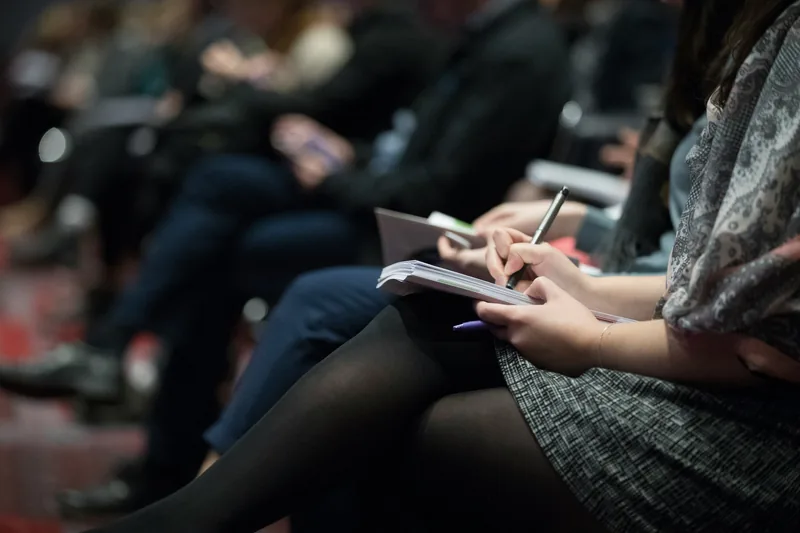 Delegates taking notes during a conference session