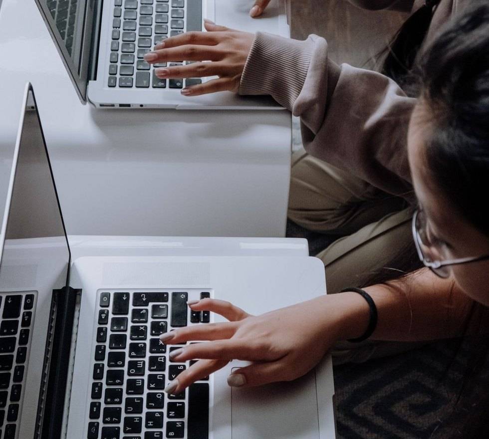 Two people working on laptops at a desk