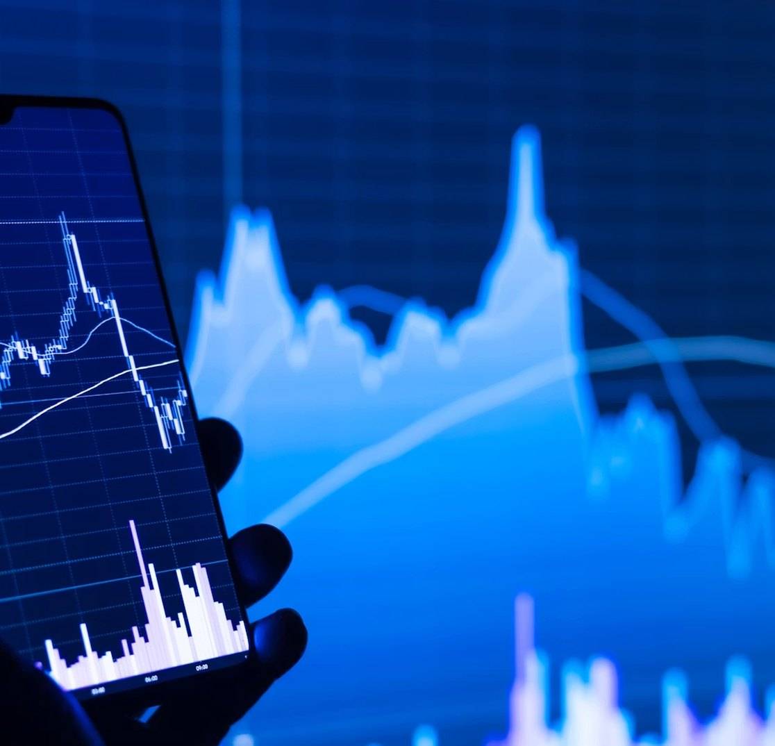 A phone showing financial charts against a blue market graph