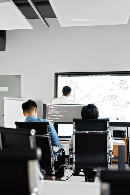 Learners at computers in a classroom, facing a whiteboard